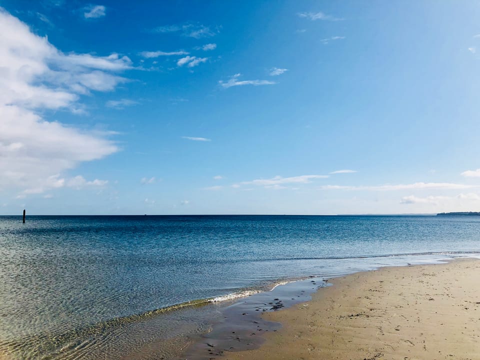 Klares Ostseewasser an einem Sandstrand unter blauem Himmel